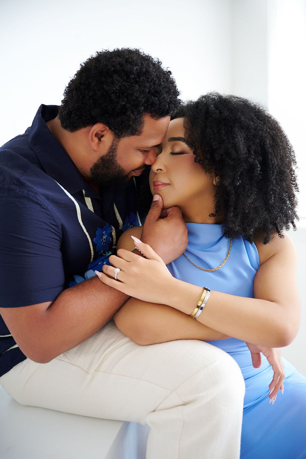 A couple shares an intimate embrace, the man tenderly kissing the woman's forehead as she closes her eyes peacefully. NJ Studio engagement