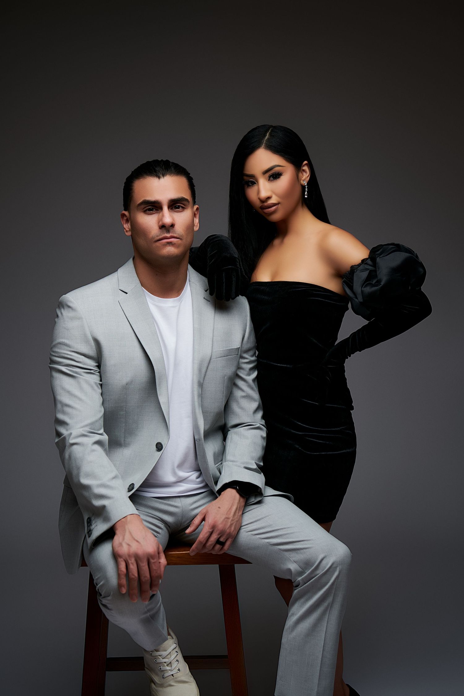 Studio fashion portrait of a couple in contrasting black and white outfits posing against dark background.