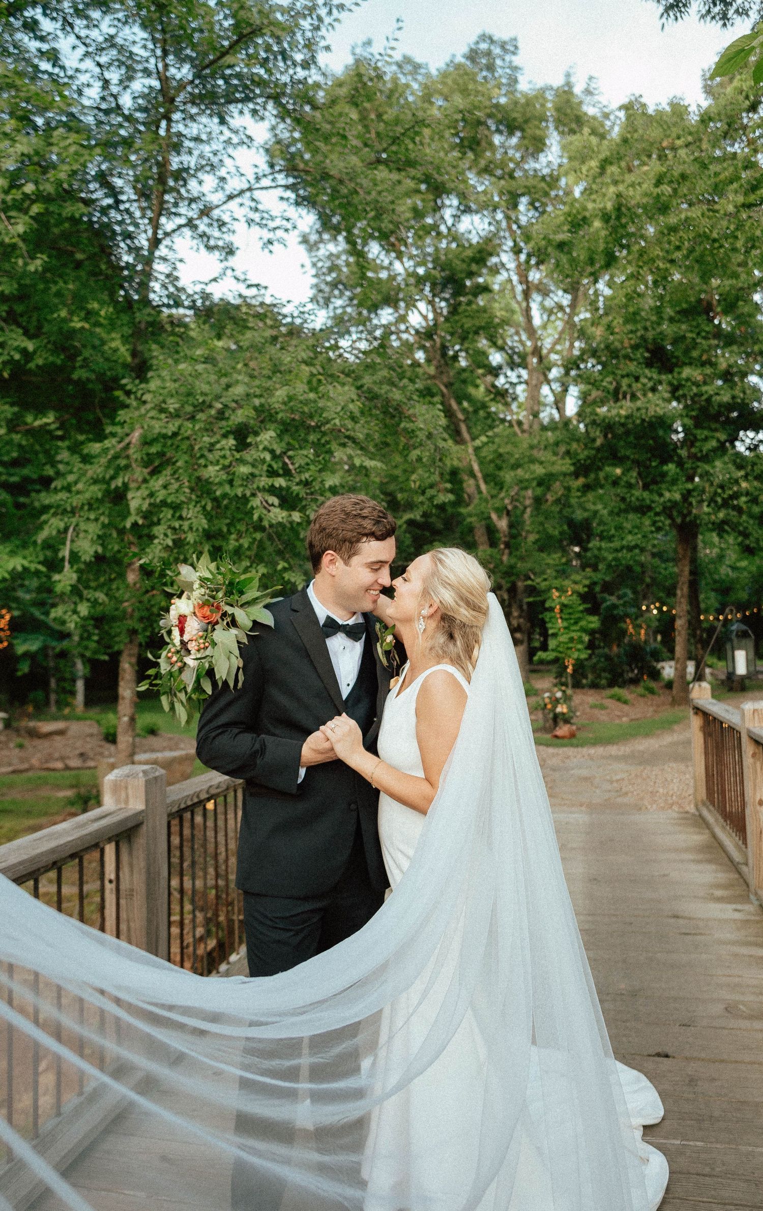 Newlyweds sharing romantic moments on a wooden bridge with flowing veil.
