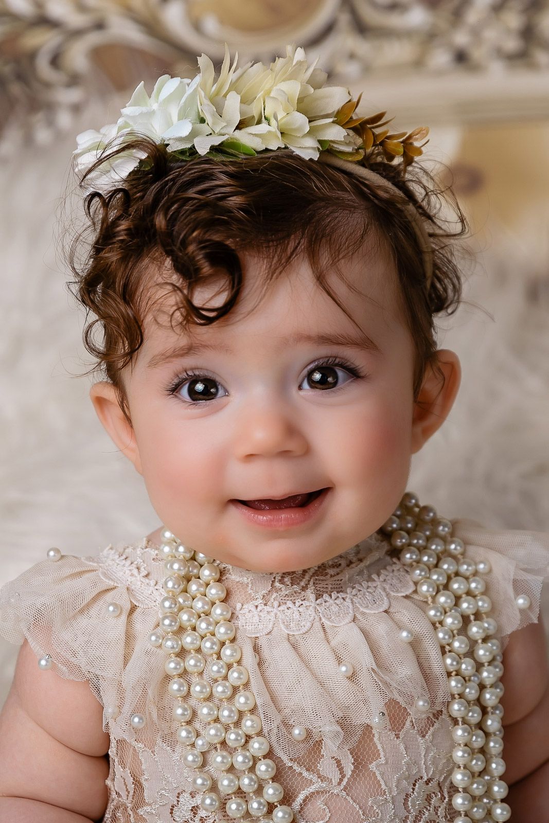 A series of close-up photos showing a baby wearing a delicate white lace dress adorned with pearl details.