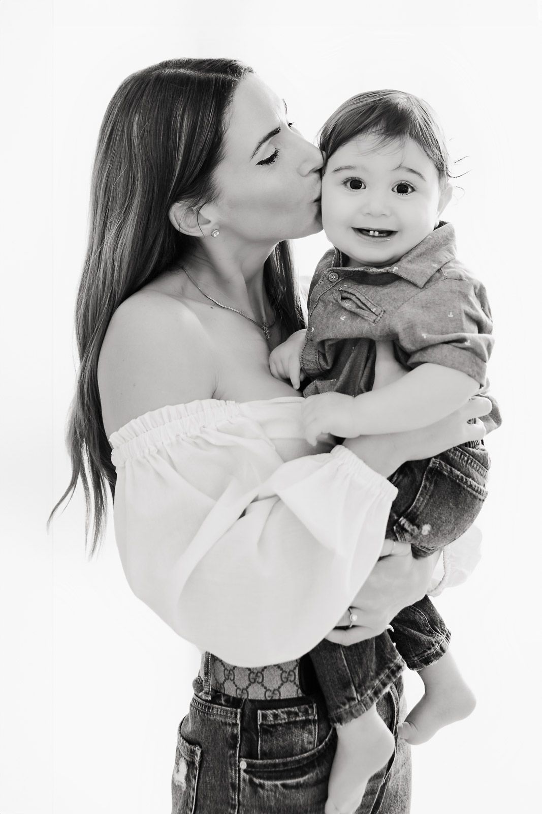 Black and white photo series showing tender moments between parent and baby in casual clothing against white backdrop.