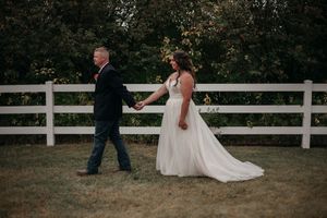 A couple shares a romantic moment on a white-fenced patio during their wedding celebration.