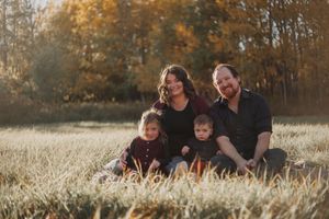 A family sits together in a golden autumn field during a sunset photo session.
