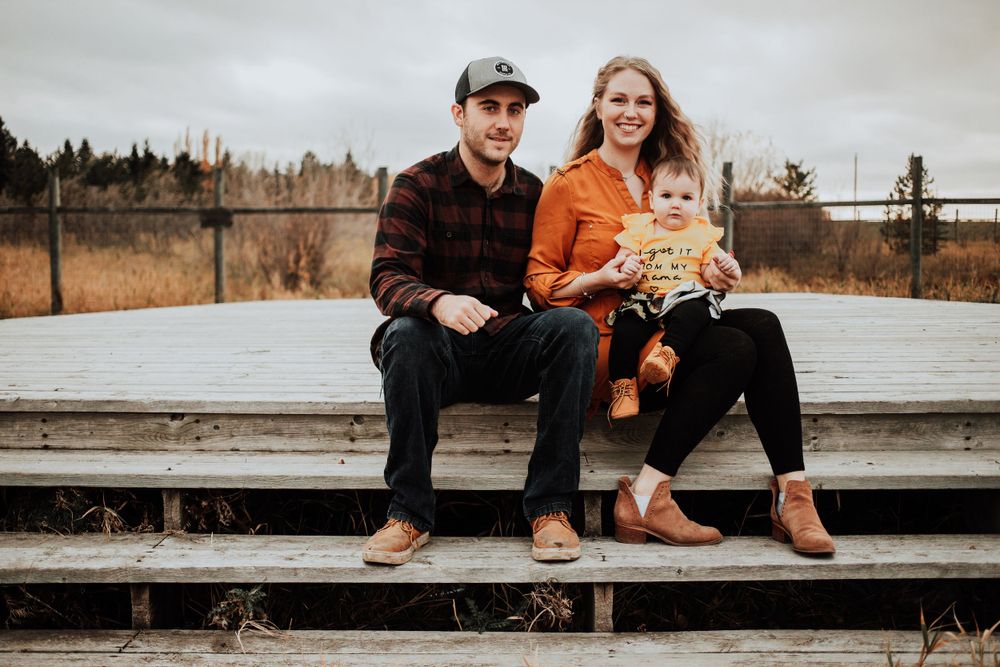 Family sitting together on wooden deck with autumn landscape in background.