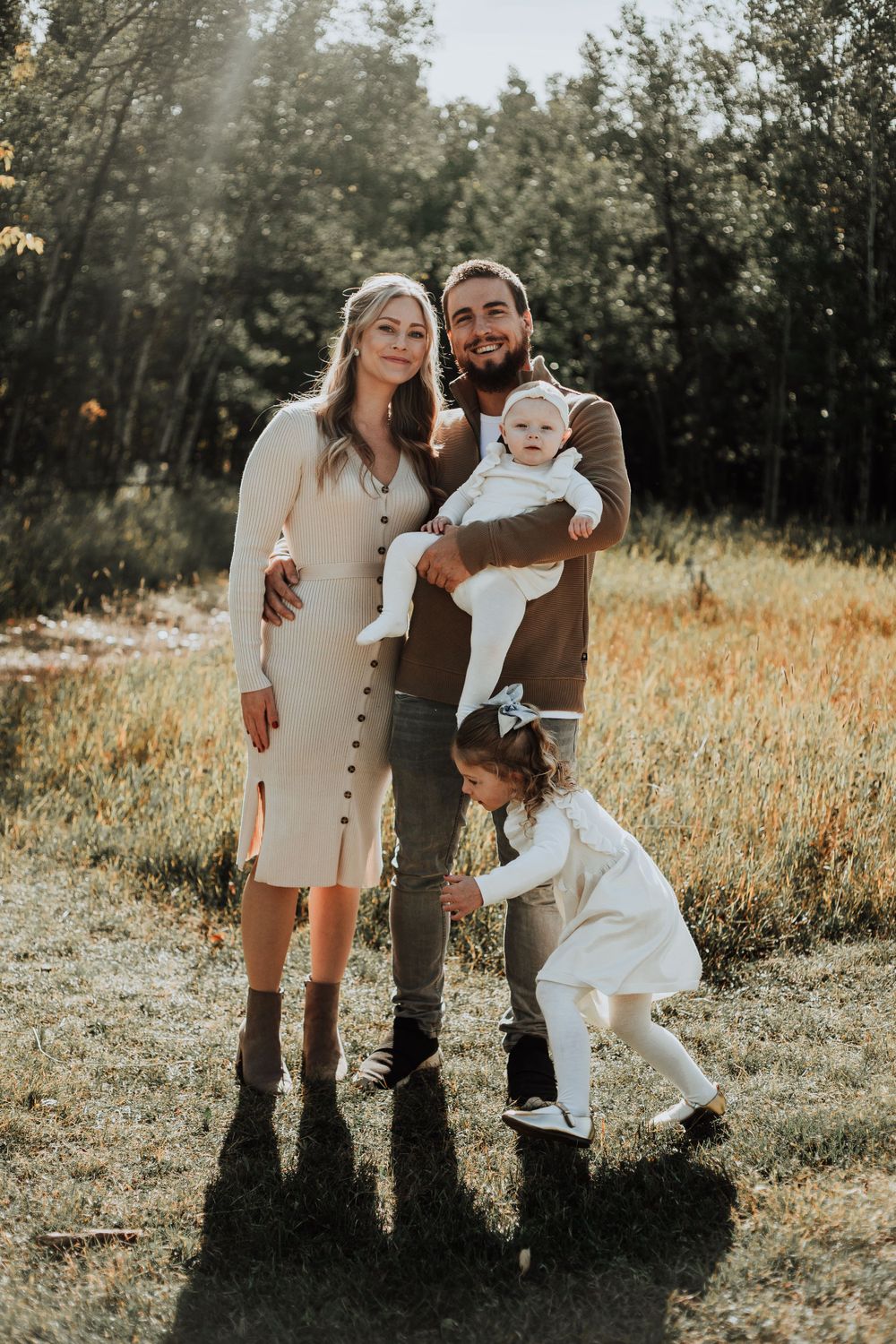 Sunlit family portrait in rustic field with warm autumn colors.