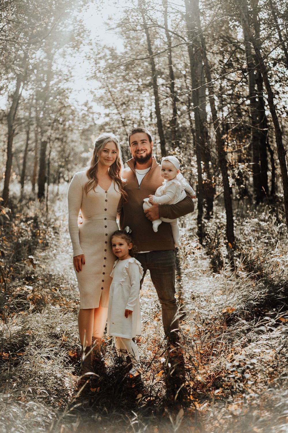 Beautiful family outdoor portrait in a misty forest setting with warm autumn tones.