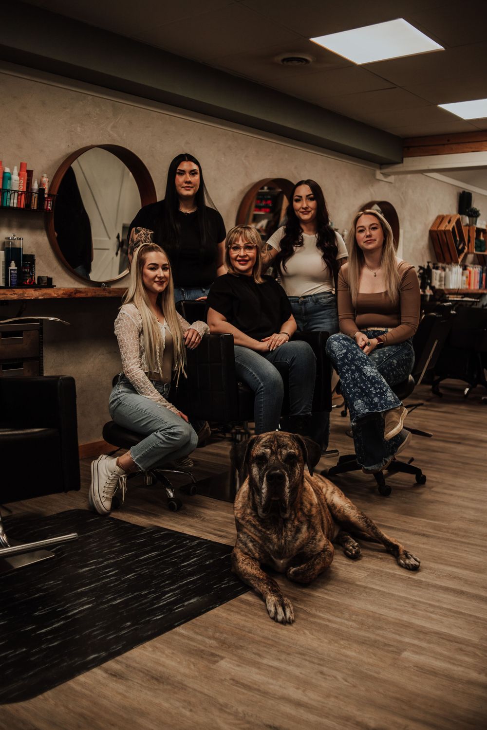 Group relaxing together in a hair salon with a large brown dog laying on the floor.