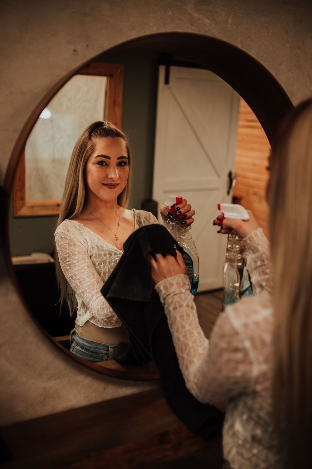 Mirror reflection shows someone holding styling equipment in a warm-toned salon setting.