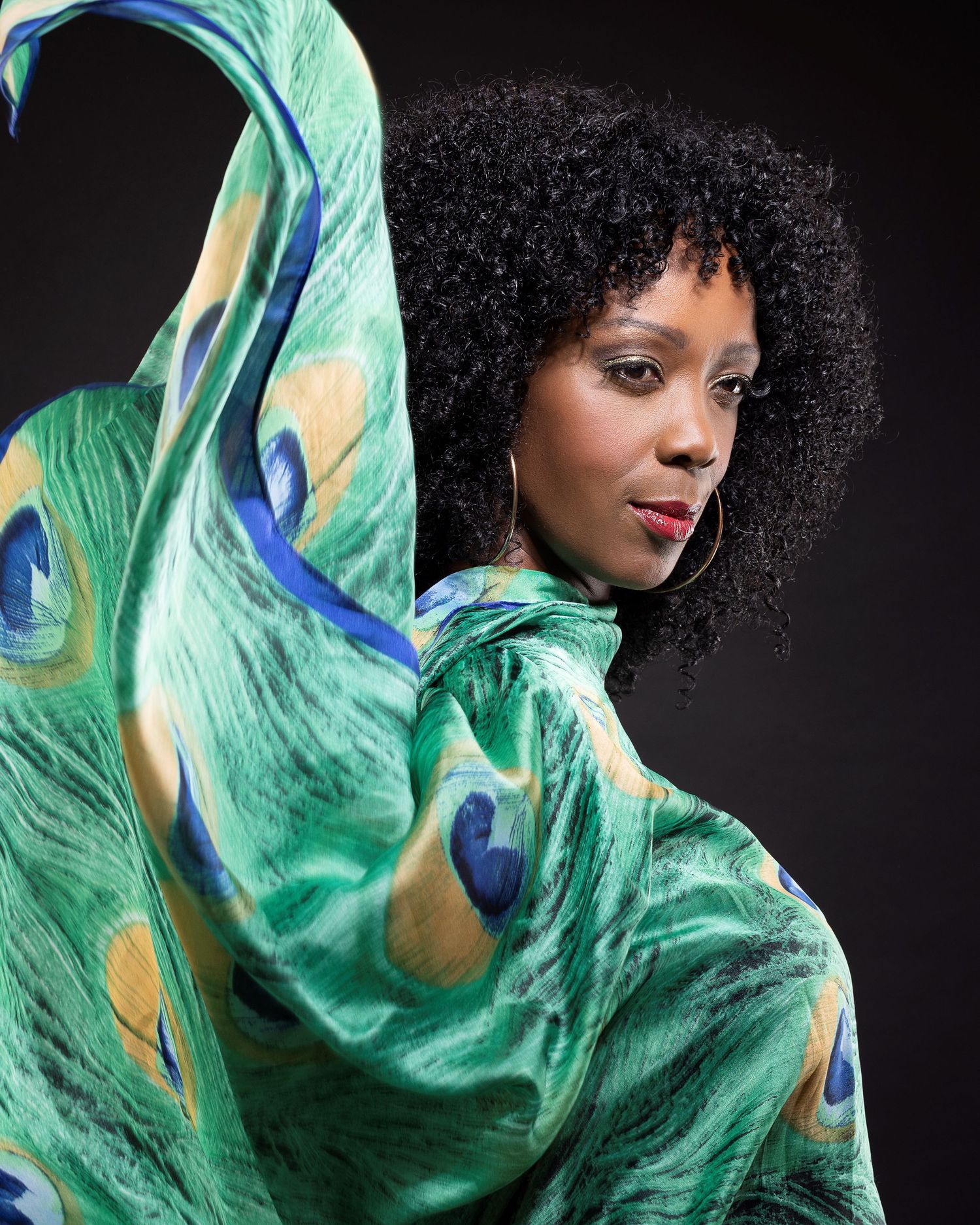 An exotic look with iridescent greens and blues on the eyes. A natural afro style.
