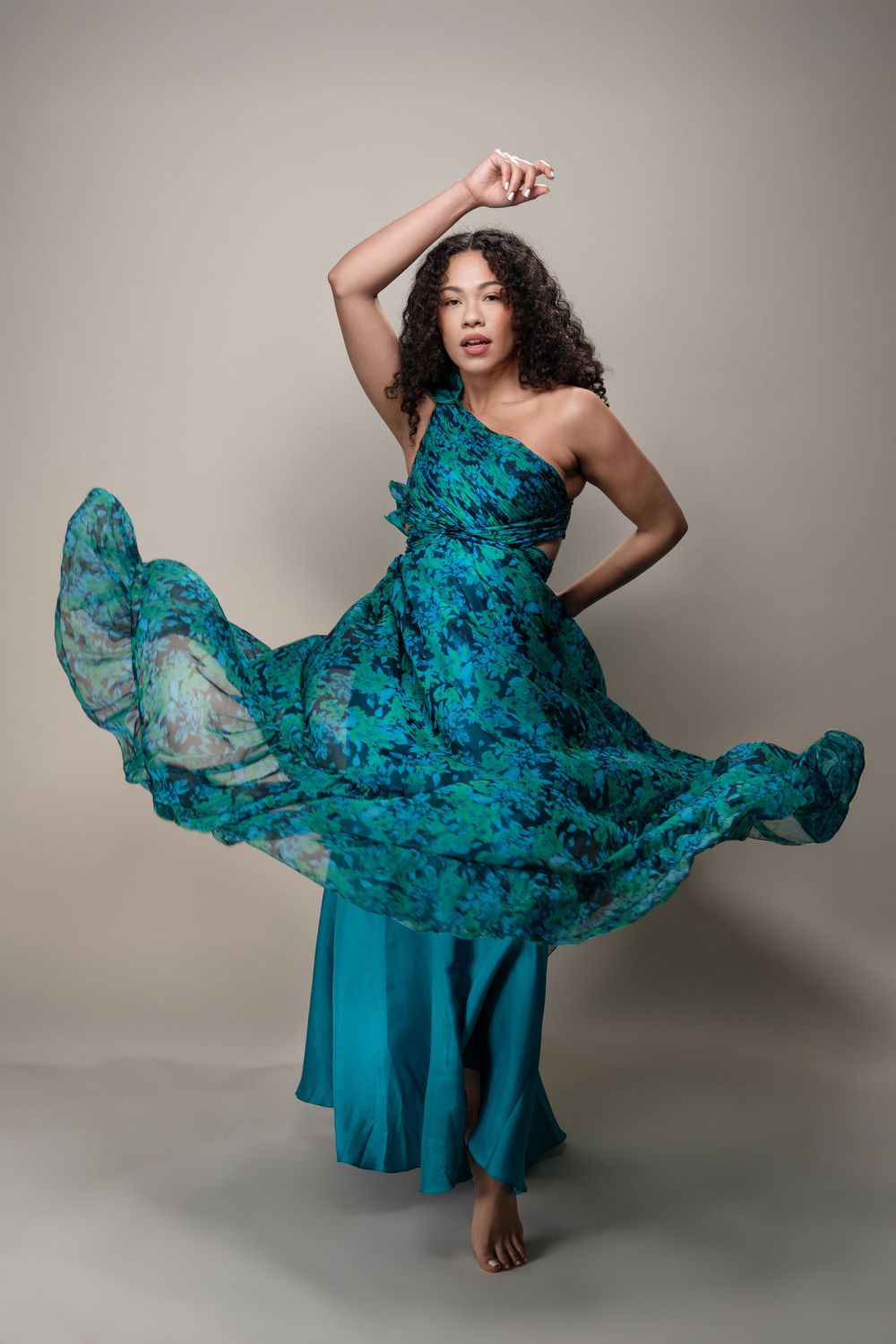 A flowing turquoise dress swirls and billows elegantly in a dynamic fashion photoshoot against a neutral backdrop.