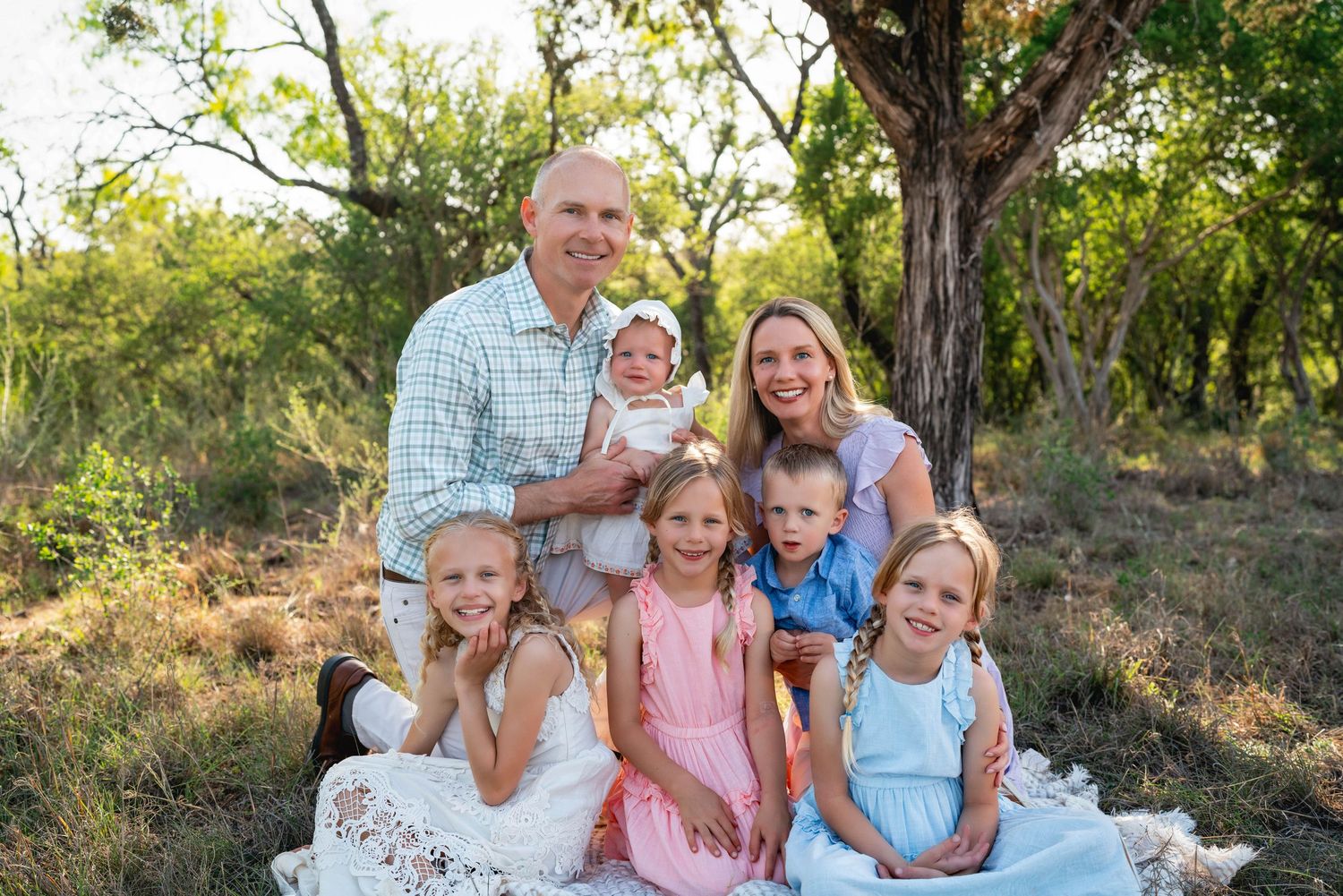 A series of outdoor family portraits taken in a natural setting with trees and greenery in the background.