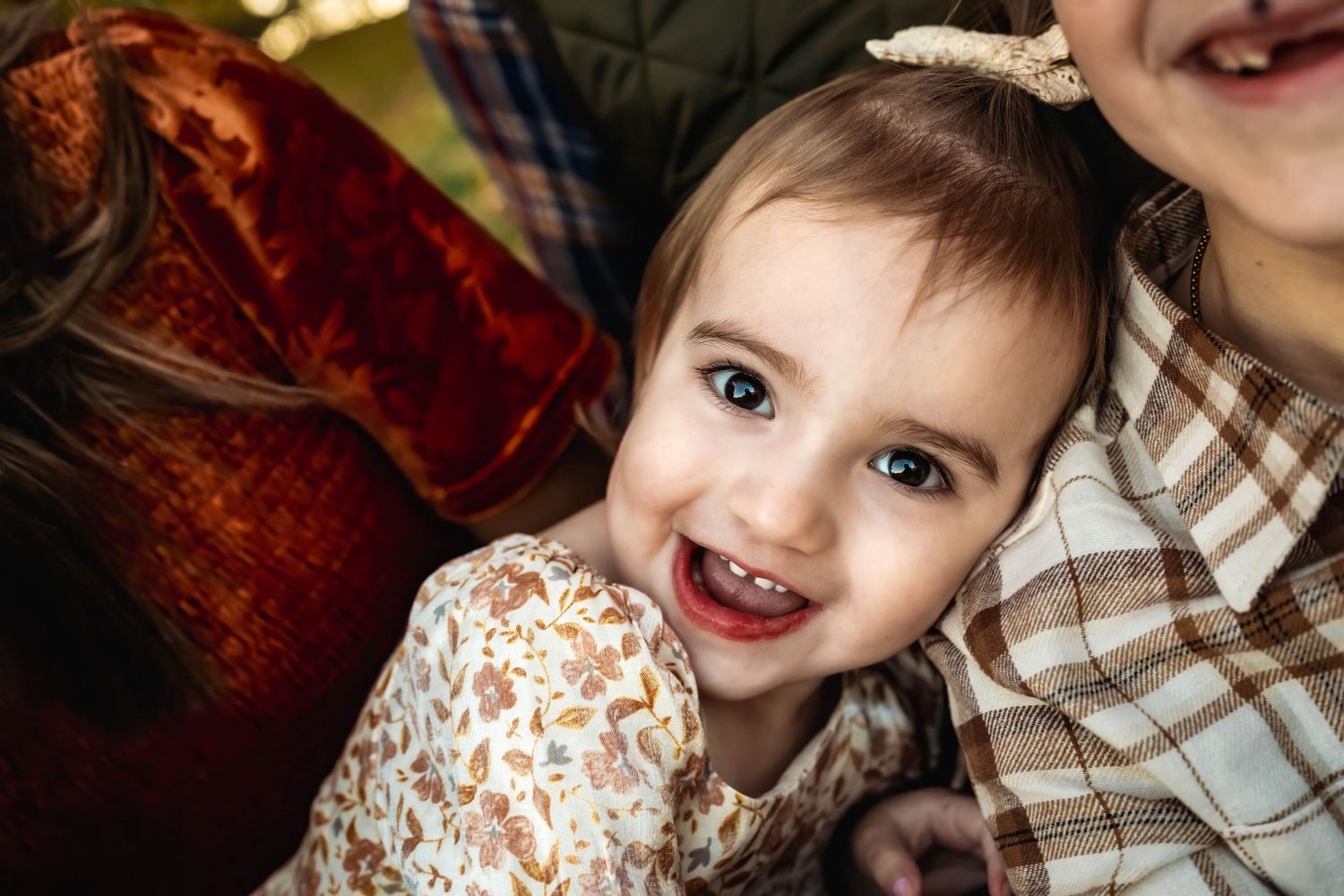 A child poses playfully on a red velvet couch during a holiday photo shoot.