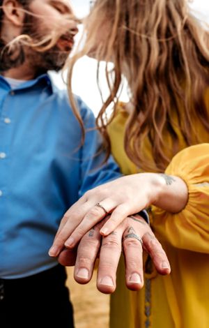 Close-up of hands showing engagement rings against yellow and blue clothing.