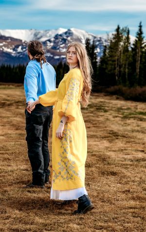 Person in yellow dress and companion in blue viewing snowy mountain vista.