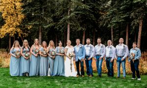 Full wedding party in powder blue and light suits posed outdoors with fall foliage.