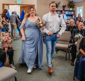 Wedding party members walking down the aisle in blue and white attire.