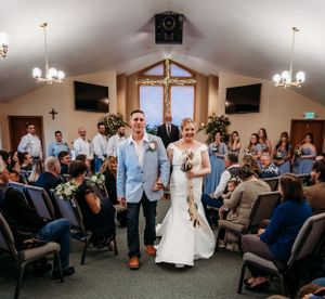 Wedding ceremony in a church with light wood beams and chandeliers.