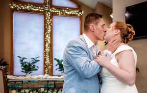 Romantic wedding moment in front of a window decorated with twinkle lights.
