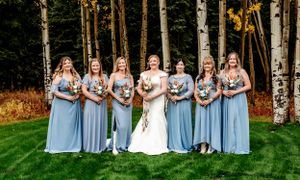 Wedding party in powder blue dresses posed in front of birch trees.