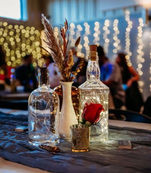 Wedding reception decor featuring glass bottles, dried flowers and string lights.
