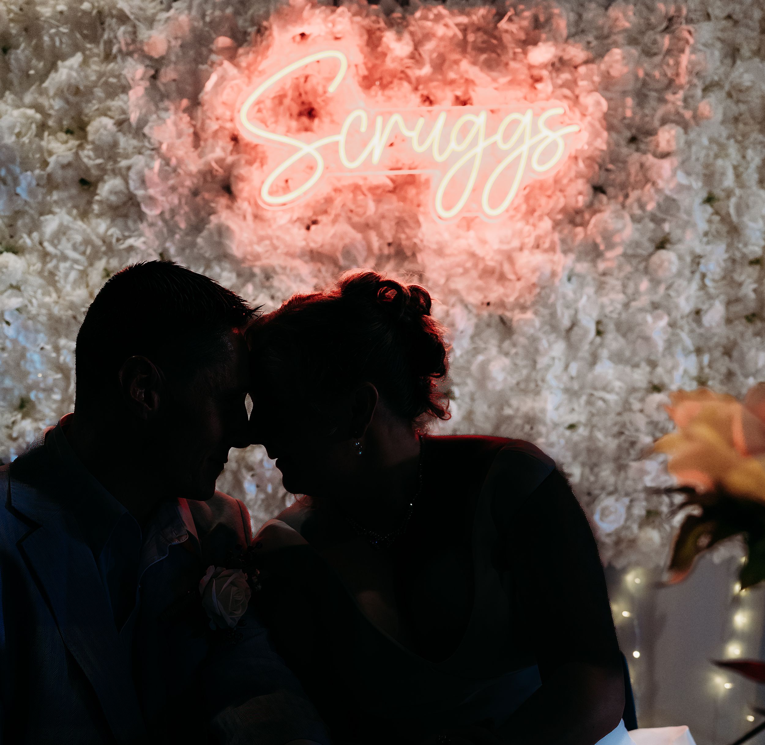 Silhouettes of a couple under a pink neon 'Savage' sign at night.