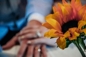 Close-up of engagement rings with a vibrant sunflower in soft focus.