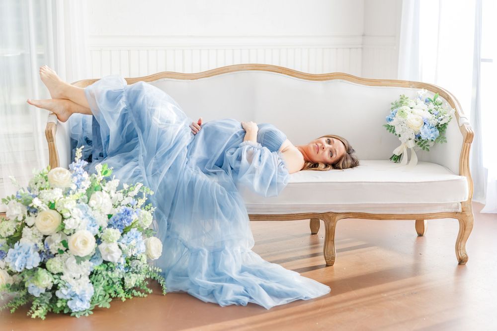 Dreamy maternity portraits in soft natural light with blue gown and white and blue hydrangea floral arrangements.