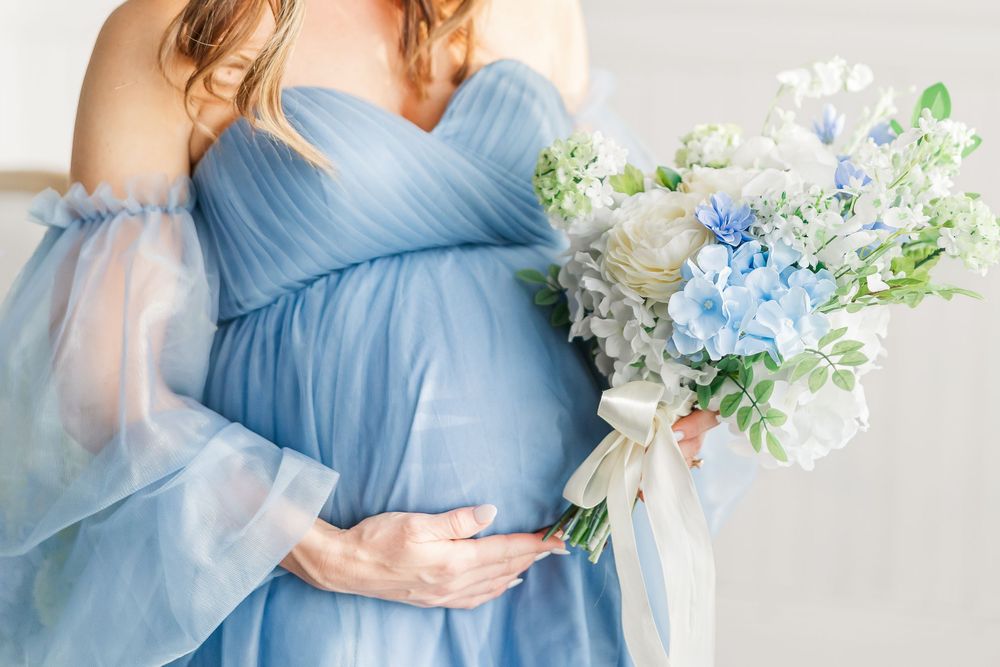 A collection of ethereal light blue maternity gown photos with delicate white and blue floral arrangements.