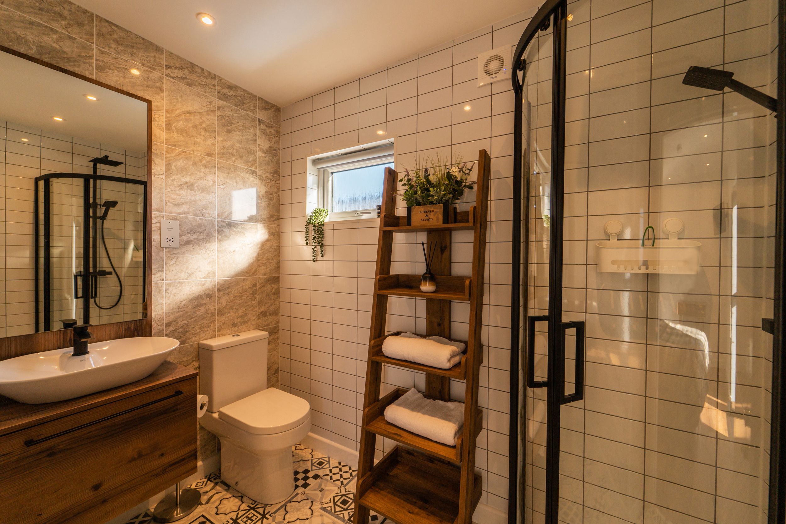 Contemporary bathroom with glass shower enclosure, wooden storage shelf, and white subway tile walls.