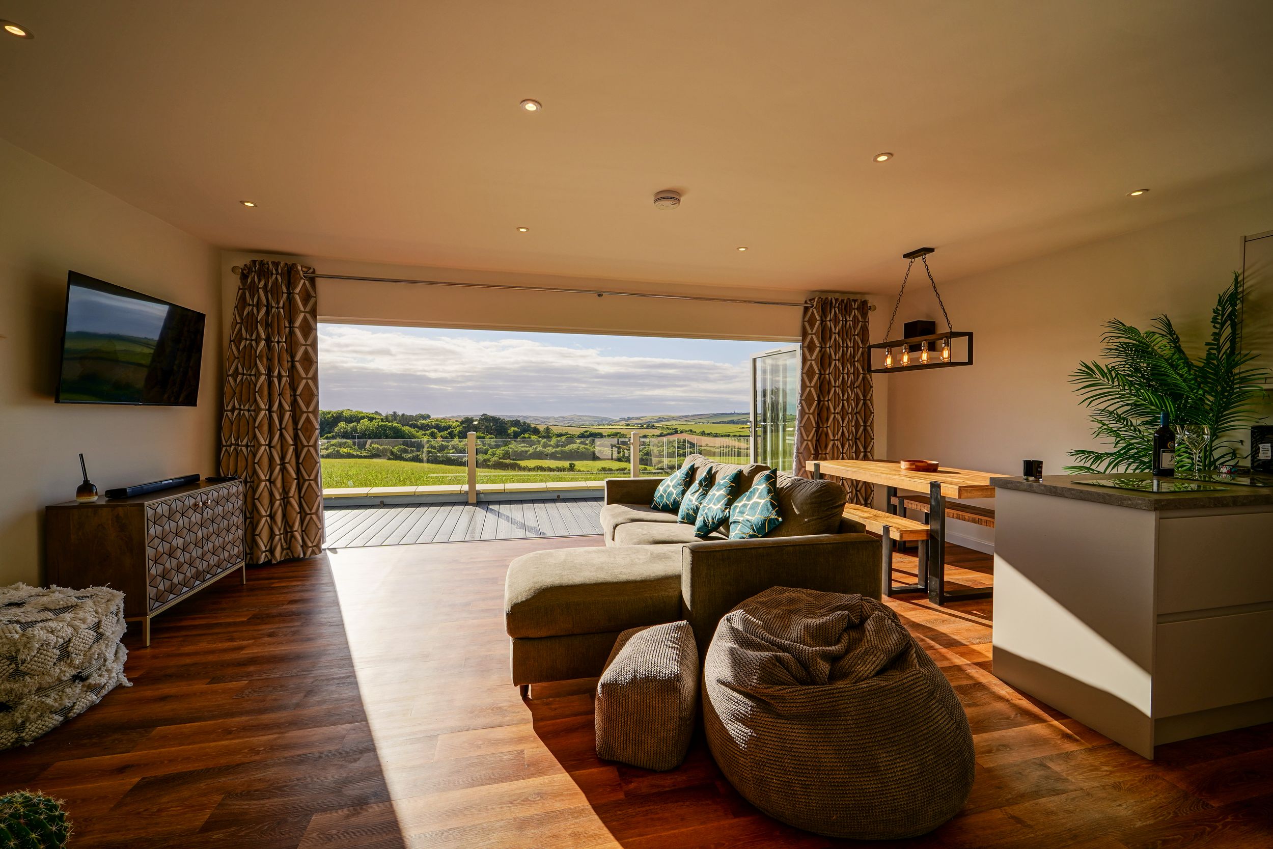 Modern living room with hardwood floors and panoramic mountain views through large windows and sliding glass doors.