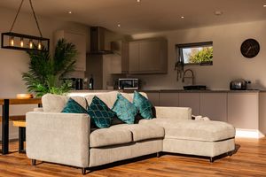 Modern open concept living room with beige sectional sofas and recessed lighting in a luxury interior.
