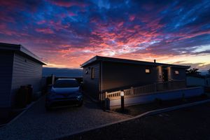 Dramatic sunset sky with vibrant pink and blue clouds above mobile homes in a residential community.