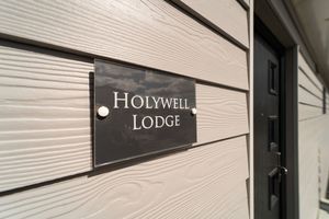 Exterior view of Holywell Lodge entrance with white siding and black trim details.