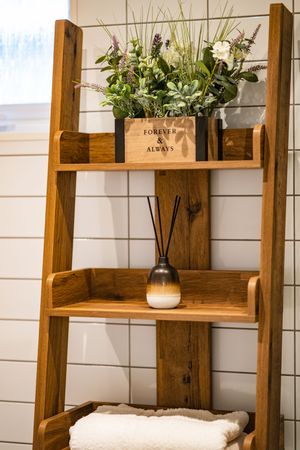 Rustic wooden shelves display decorative plants and vases against a white textured wall in a modern farmhouse style.