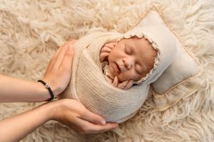 Newborn photographer Exeter- mother gently holding wrapped newborn.