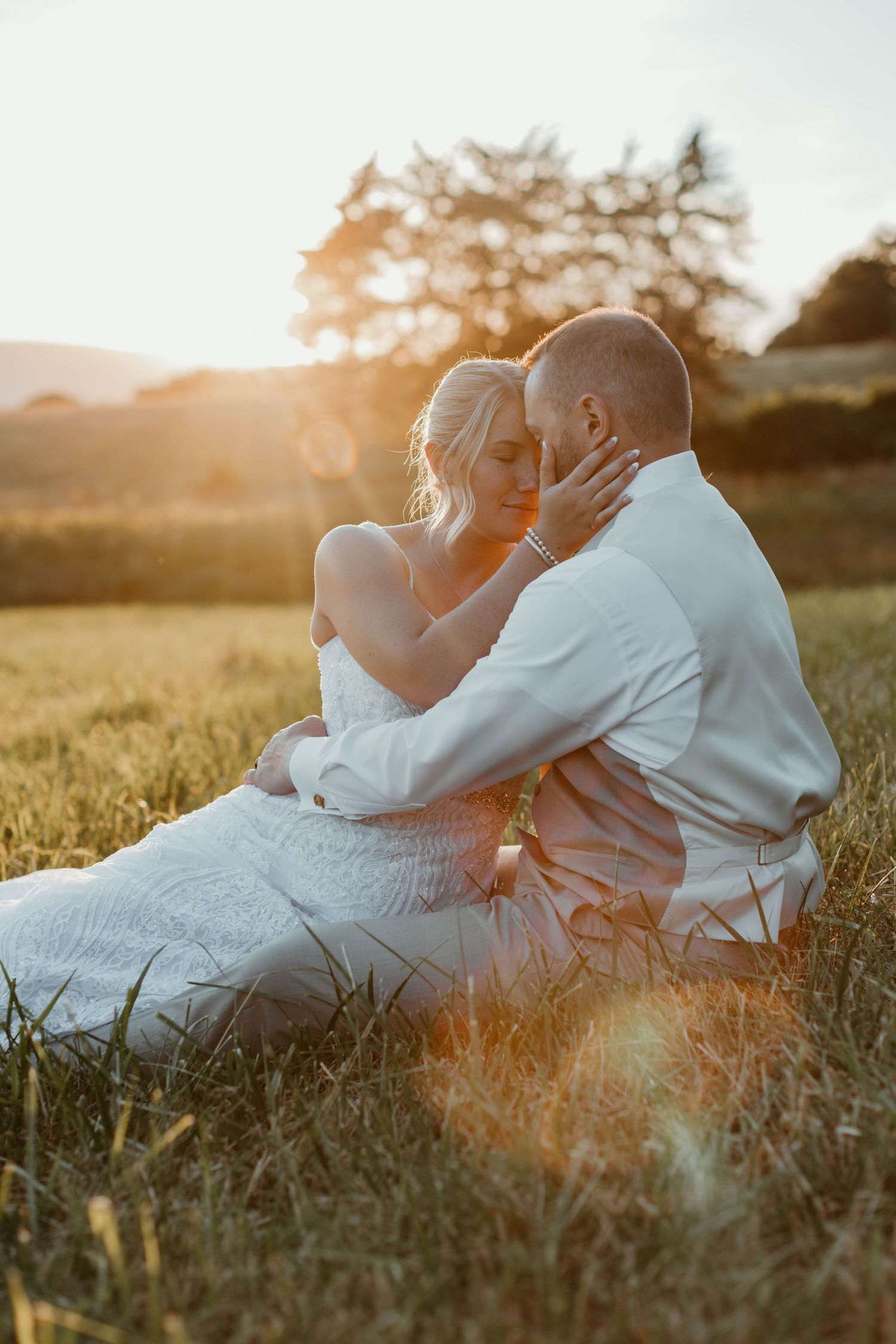 Intimate couple's portrait session at golden hour in a serene meadow setting.