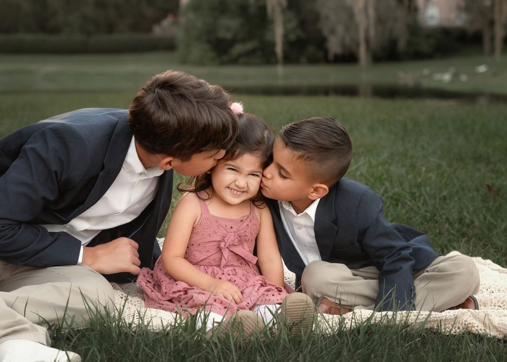 A couple lies on grass in a romantic moment while wearing formal attire and a pink dress.