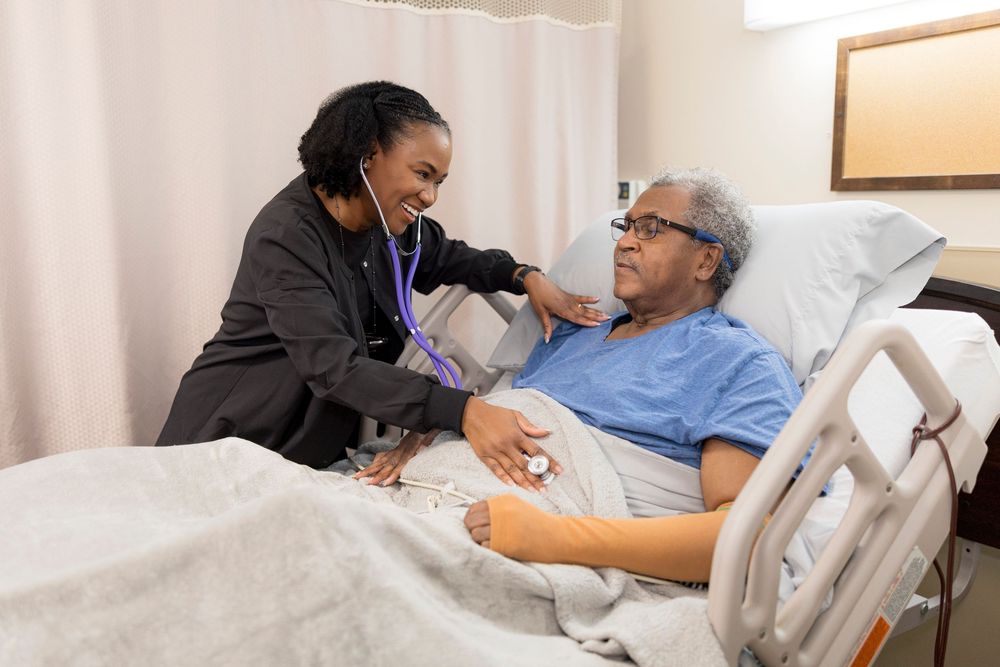 Healthcare worker explains medical information to patient resting in hospital bed while reviewing documents together.