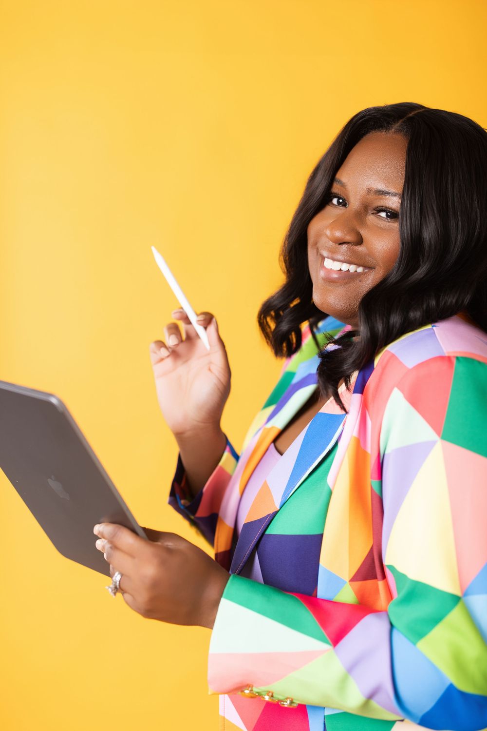 Multiple shots of a person wearing a vibrant geometric print dress against a bright yellow background.
