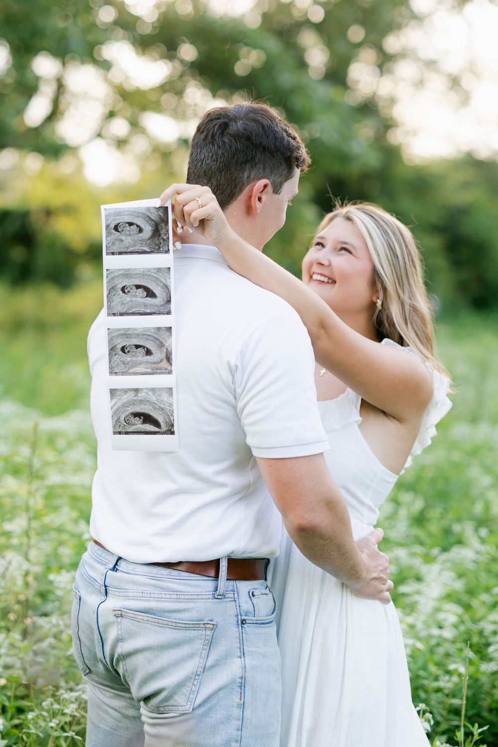 A couple embraces intimately in a field of white wildflowers during a outdoor photo session.