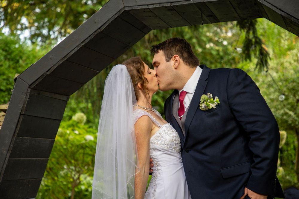 a bride and groom kissing under an octagon arbour
