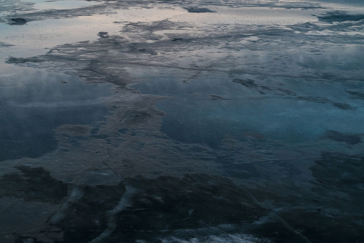Aerial view of dark blue ocean waters meeting icy formations creating a moody winter seascape.