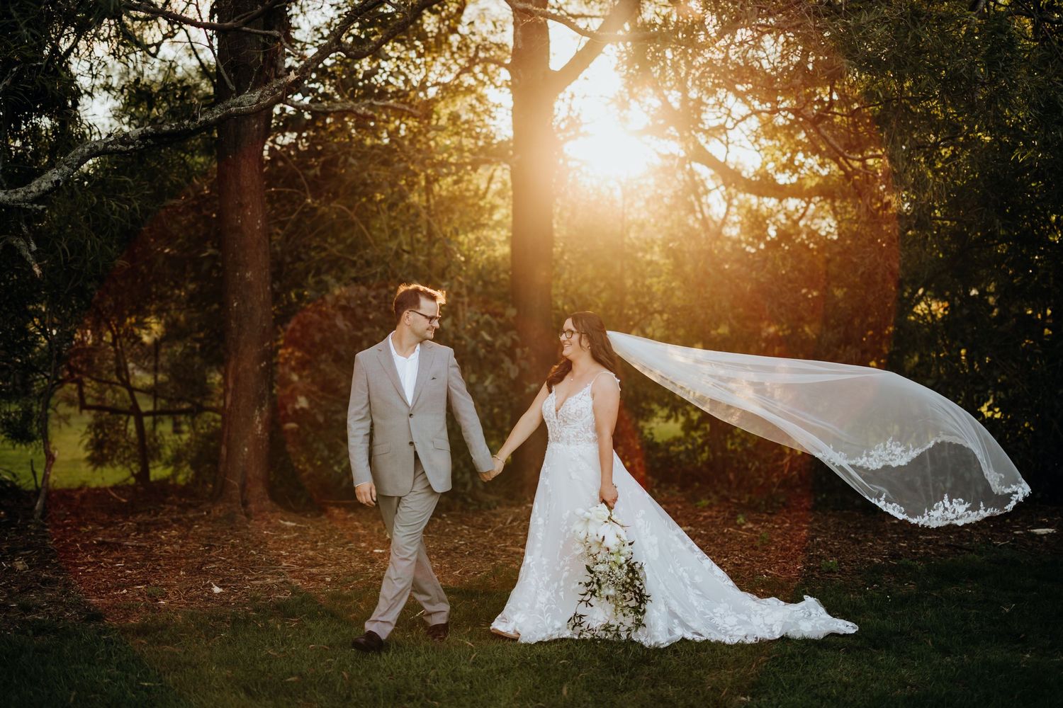 A couple shares romantic moments during golden hour sunset in a forested wedding venue setting.