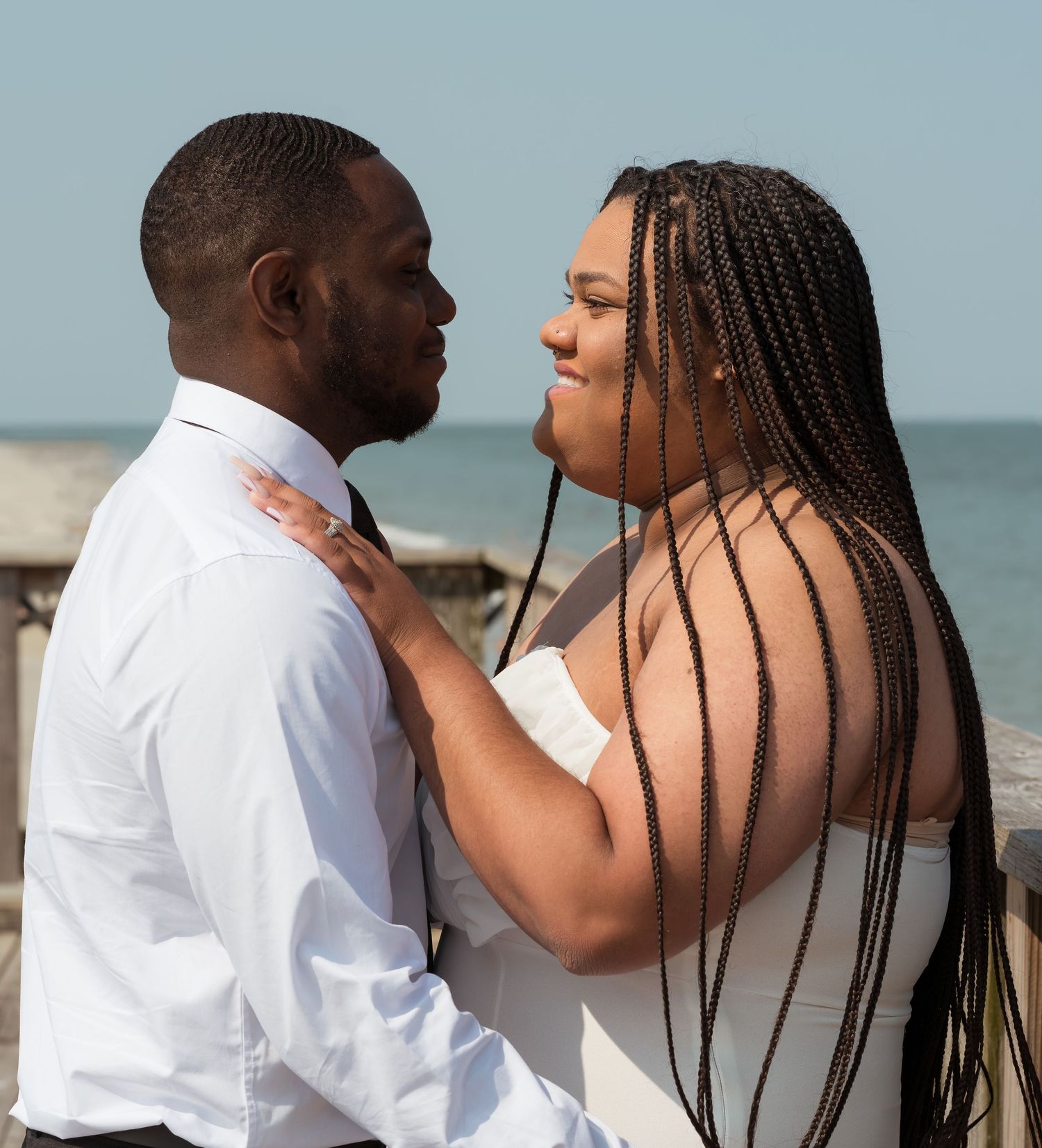 A romantic couple shares an intimate moment on the beach with waves in the background.
