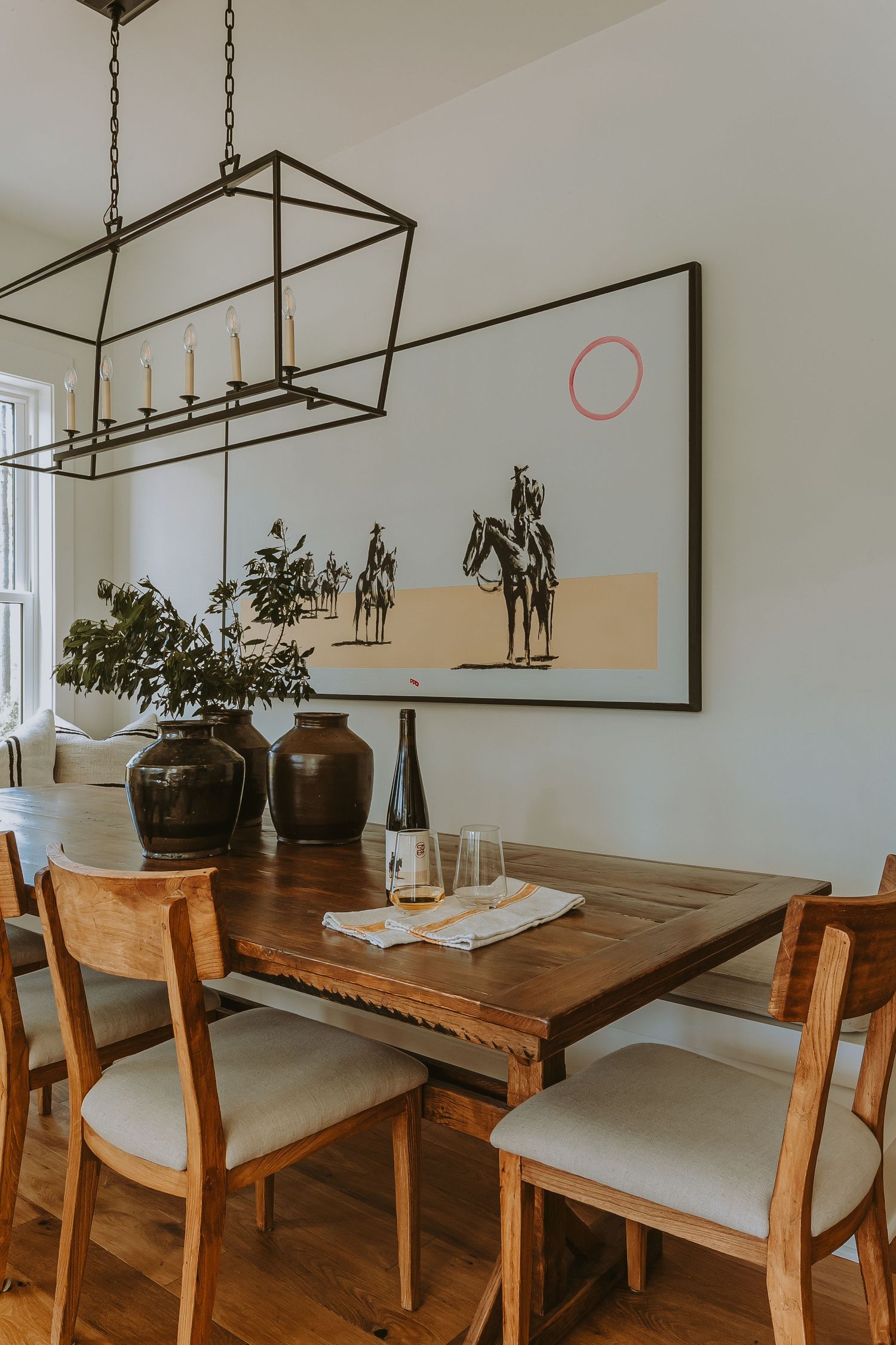 Modern dining room features a long wooden table with upholstered chairs and minimalist pendant lighting above.