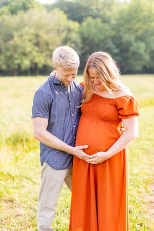 Tender outdoor maternity photo with couple embracing in a sunlit field in Springfield, Missouri.