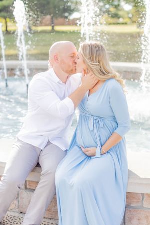 Romantic maternity photo by fountain with couple in light colored outfits in Springfield, Missouri.