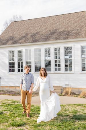 Couple in casual and formal wear walking together on grass in front of white building in Springfield, Missouri.