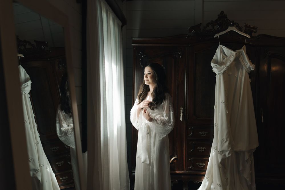 White wedding dresses hanging on display in a dark, moody bridal boutique interior.