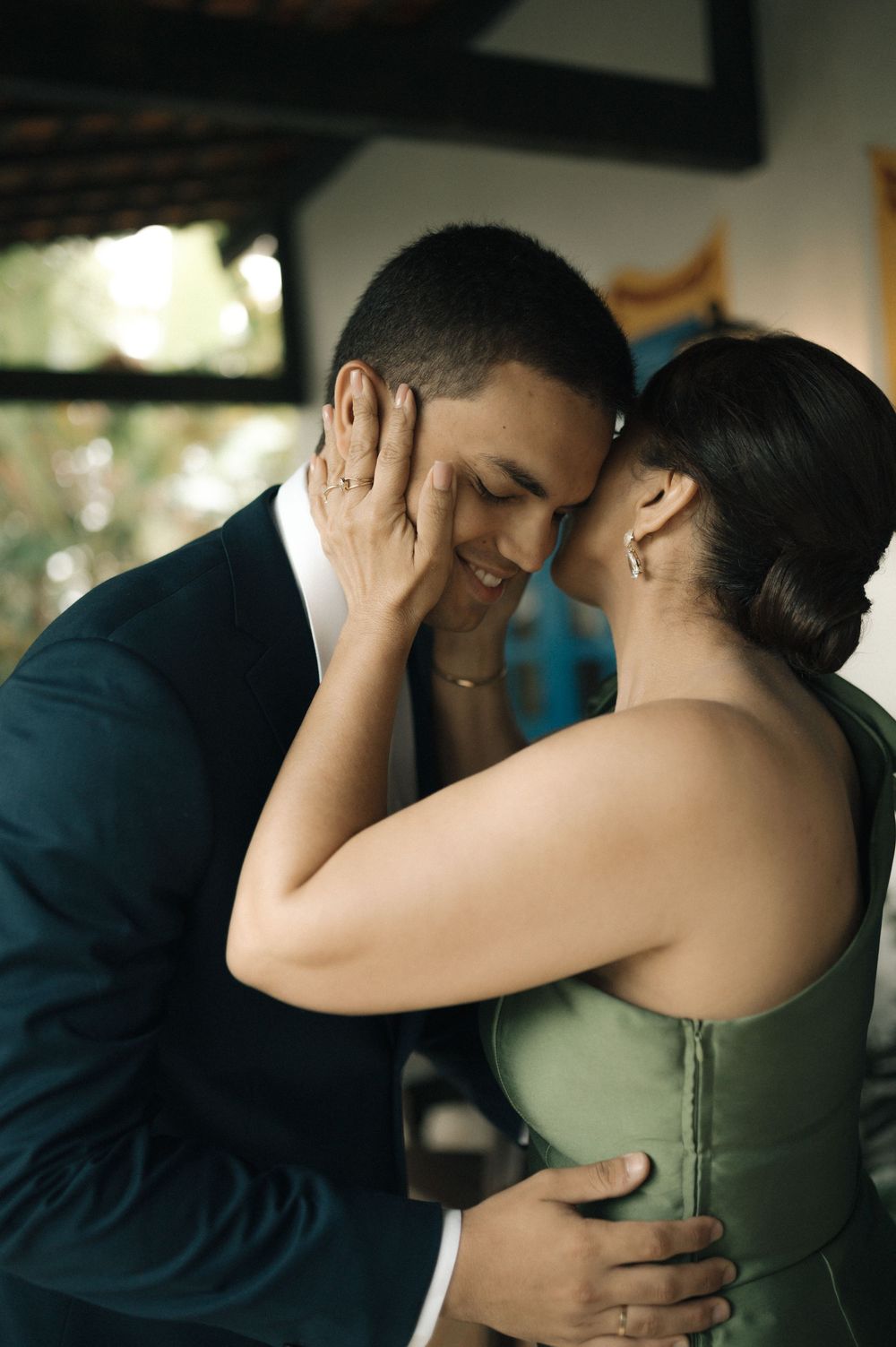 A tender moment shared between a couple in formal attire, with her hand gently placed on his face as they embrace.